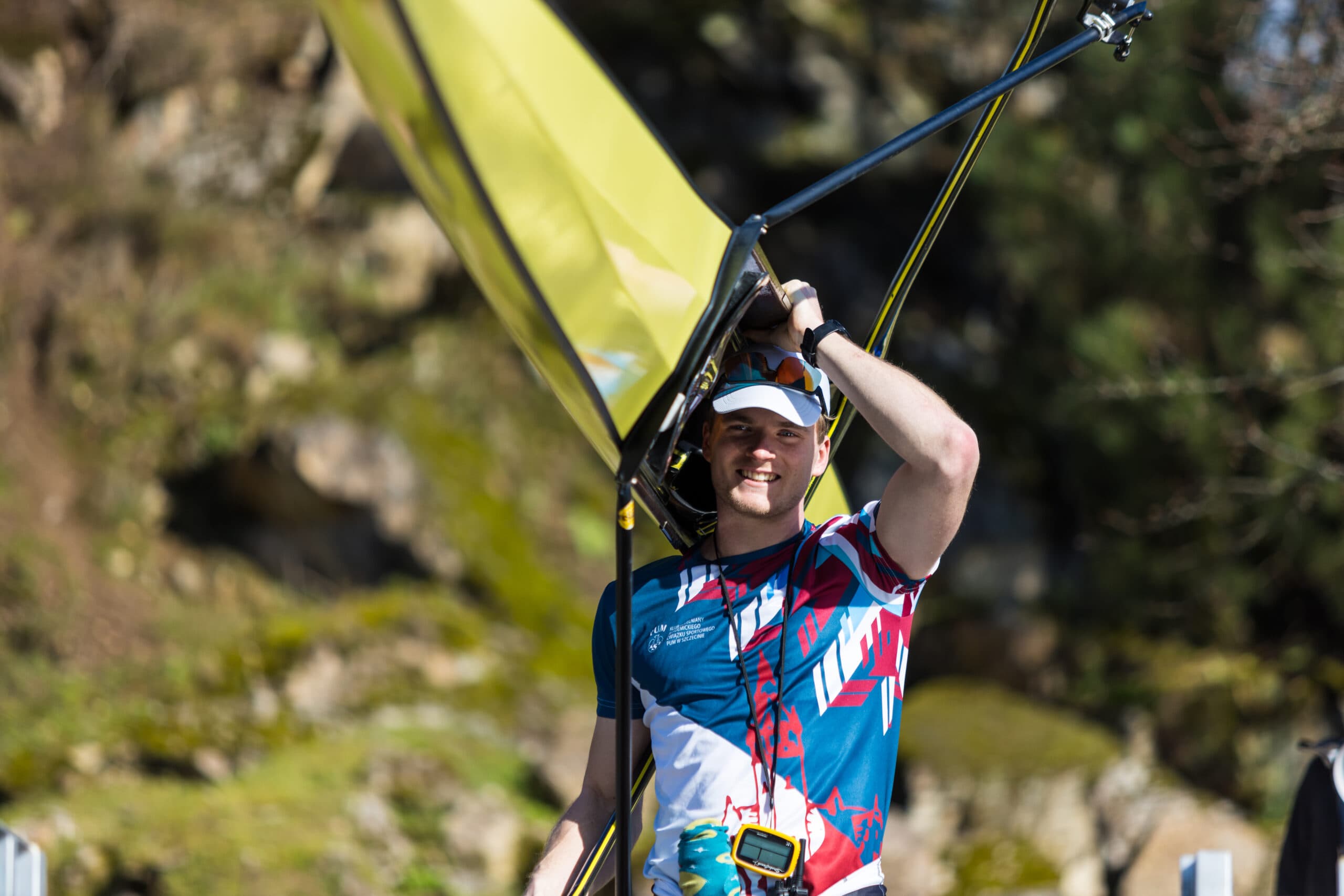 Athlete carrying a rowing shell beside the water